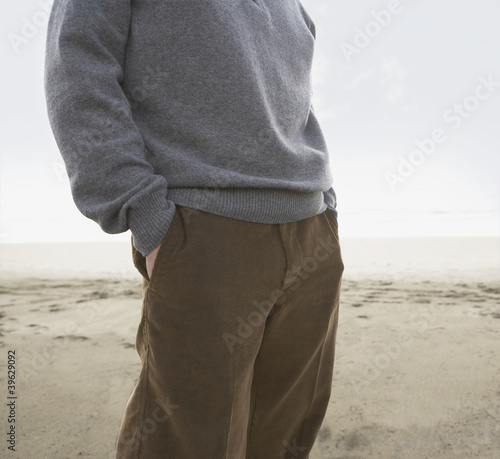 Photo: Man standing on the beach with his hands in his pockets Man standing on the beach with his hands in his pockets