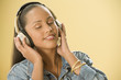Studio shot of a Dominican woman listening to music on headphones