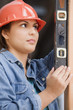 Hispanic female construction worker using a level