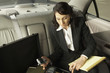 Businesswoman working in the backseat of a car