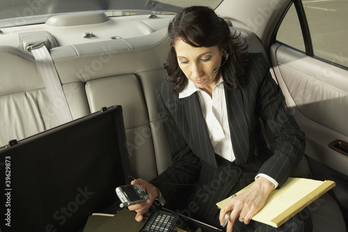 Photo: Businesswoman working in the backseat of a car Businesswoman working in the backseat of a car