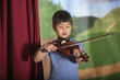 Young Asian girl playing violin at recital