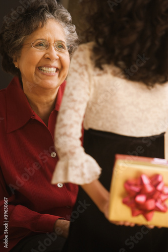 Photo: Hispanic granddaughter giving grandmother gift Hispanic granddaughter giving grandmother gift