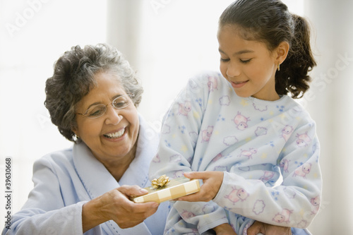Photo: Hispanic granddaughter giving grandmother gift Hispanic granddaughter giving grandmother gift