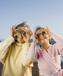 Grandmother and granddaughter holding up rocks to eyes at beach