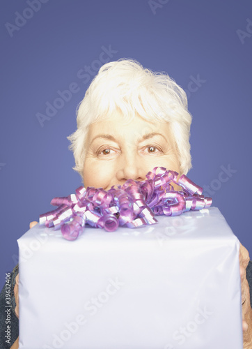 Photo: Studio shot of senior woman with gift Studio shot of senior woman with gift