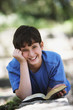 Boy smiling with book outdoors