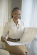 Senior African businesswoman holding blueprints