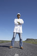 Man wearing hard hat and lab coat standing in middle of deserted road