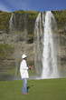 Man with hard hat and clipboard looking at waterfall
