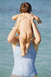 Mother holding up baby in ocean