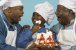 Photo: Multi-generational African male family members in chef's hats with cake Multi-generational African male family members in chef's hats with cake