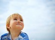 Beautiful little baby against blue sky.