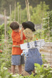 Young Hispanic boy putting hat on scarecrow