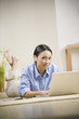 Pacific Islander woman laying on floor using laptop