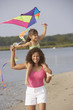 Hispanic mother and daughter flying kite on beach