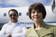 Businesswoman and male pilot standing in front of private airplane