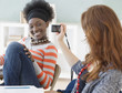 Female college student taking photograph of friend in classroom
