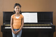 African girl standing in front on piano
