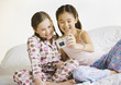Two girls taking own photograph on bed