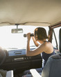 Hispanic woman looking through binoculars in car