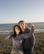 Asian couple taking own photograph at beach