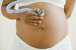 Pregnant African woman holding stethoscope on belly