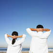 Hispanic couple with hands behind head at beach