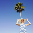 Hispanic woman wearing sunhat under palm tree