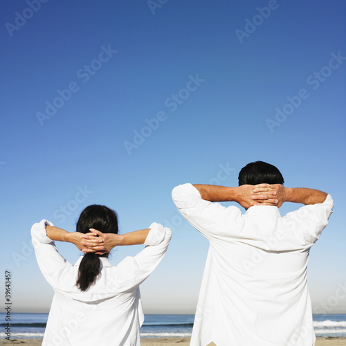Photo: Hispanic couple with hands behind head at beach Hispanic couple with hands behind head at beach