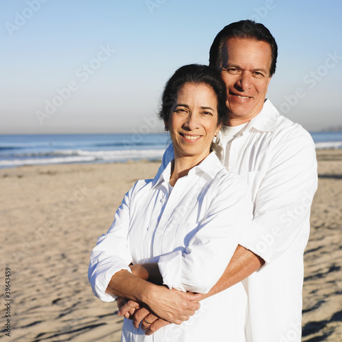 Photo: Hispanic couple hugging at beach Hispanic couple hugging at beach