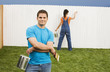 Multi-ethnic couple painting fence