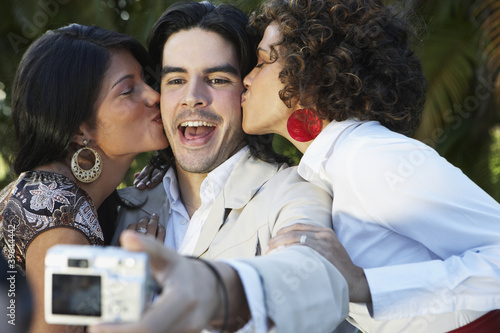 Photo: Man taking photograph of two women kissing him Man taking photograph of two women kissing him