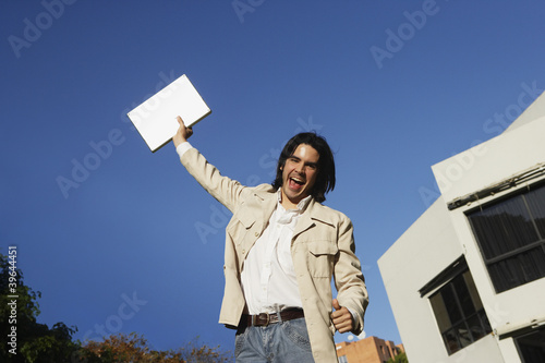 Photo: South American man holding laptop over head South American man holding laptop over head