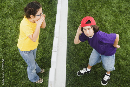 Photo: Mixed Race girl yelling to boy through fence Mixed Race girl yelling to boy through fence