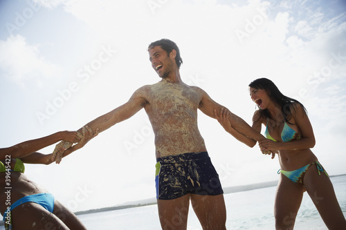 Photo: Two women pulling on man's arms Two women pulling on man's arms