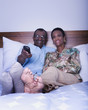Senior African couple watching television in bed