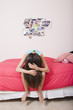 Hispanic girl sitting on bed with head down