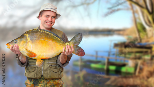 Photo: The fisherman with his big Carp at a beautiful lake. The fisherman with his big Carp at a beautiful lake.