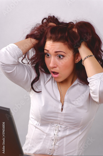 Photo: Woman with surprised look in laptop screen Woman with surprised look in laptop screen
