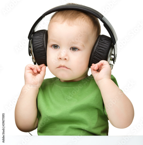 Photo: Cute little boy enjoying music using headphones Cute little boy enjoying music using headphones