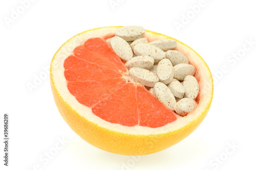 Photo: Close up of red grapefruit and pills isolated - vitamin concept Close up of red grapefruit and pills isolated - vitamin concept