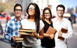 portrait of young students holding books at street