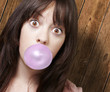young girl with a pink bubble of chewing gum against a wooden ba young girl with a pink bubble of chewing gum against a wooden ba