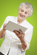portrait of senior woman touching digital tablet over green back