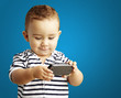 portrait of funny kid playing with mobile over blue background portrait of funny kid playing with mobile over blue background