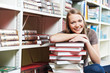 Smiling young adult woman reading  book in library