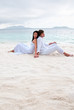 Young couple sitting on the beach near the seaside
