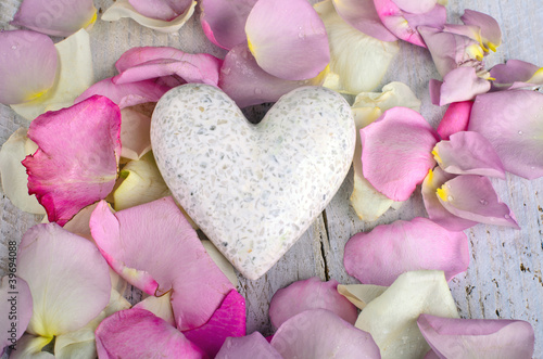 Photo: White marple heart with rose petals on wooden background White marple heart with rose petals on wooden background