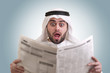 arabian businessman shocked while reading newspaper